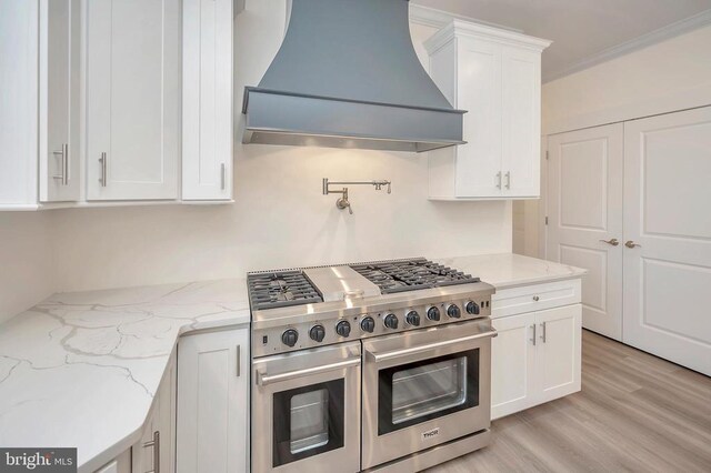 kitchen featuring white cabinetry, double oven range, light stone counters, light hardwood / wood-style floors, and custom range hood