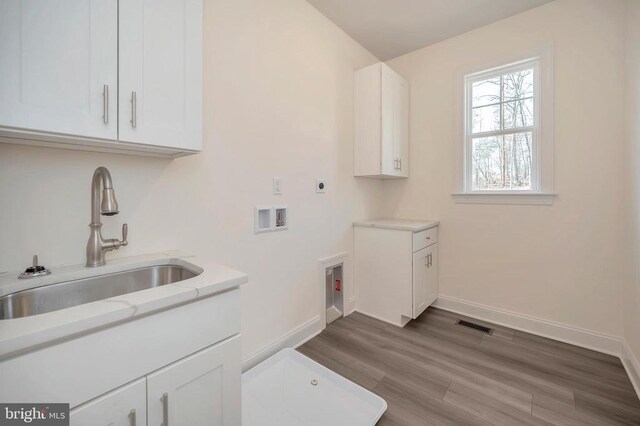 laundry room featuring hardwood / wood-style floors, sink, cabinets, hookup for a washing machine, and electric dryer hookup