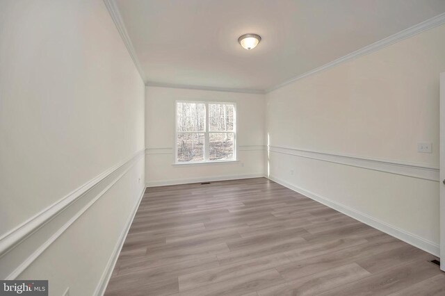 spare room with crown molding and light wood-type flooring