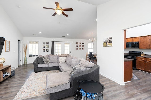 living room with visible vents, high vaulted ceiling, ceiling fan with notable chandelier, dark wood finished floors, and baseboards