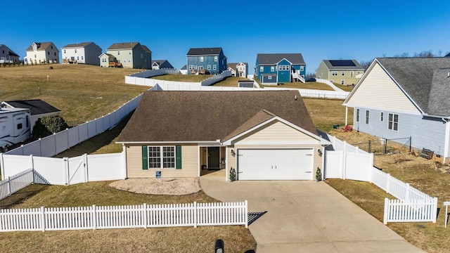 view of front of home featuring a front yard, driveway, an attached garage, a fenced backyard, and a residential view