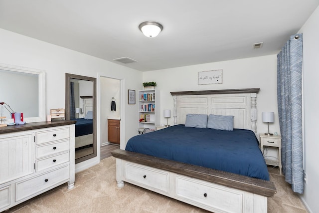 bedroom featuring visible vents, light colored carpet, and connected bathroom