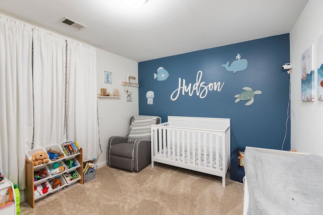 bedroom with visible vents, a nursery area, and carpet flooring