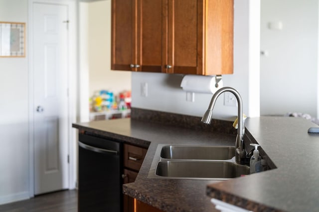 kitchen with dishwasher, dark countertops, brown cabinets, and a sink