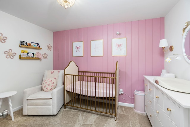 bedroom featuring light colored carpet, baseboards, a nursery area, and a sink