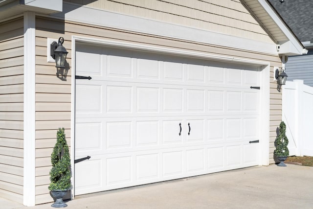 garage featuring concrete driveway and fence