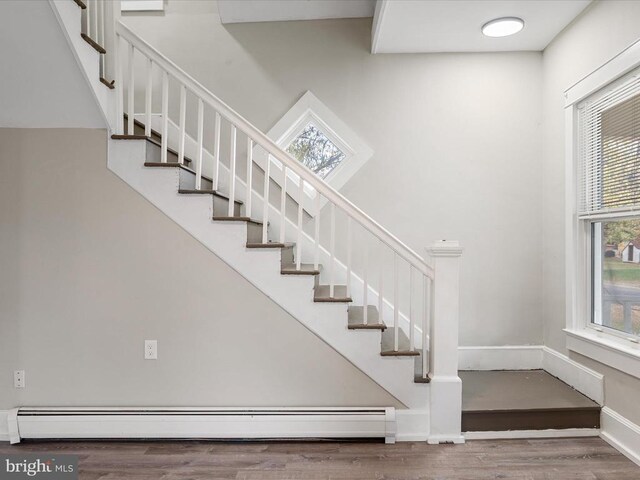 stairway featuring hardwood / wood-style flooring and a baseboard heating unit