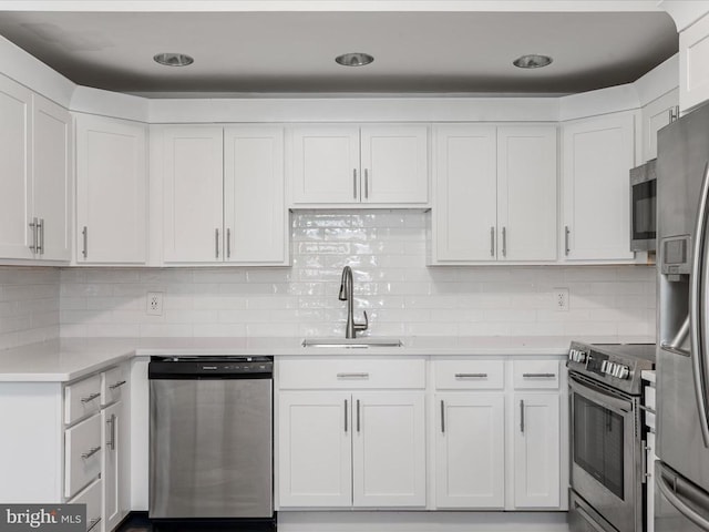 kitchen featuring tasteful backsplash, sink, white cabinets, and appliances with stainless steel finishes