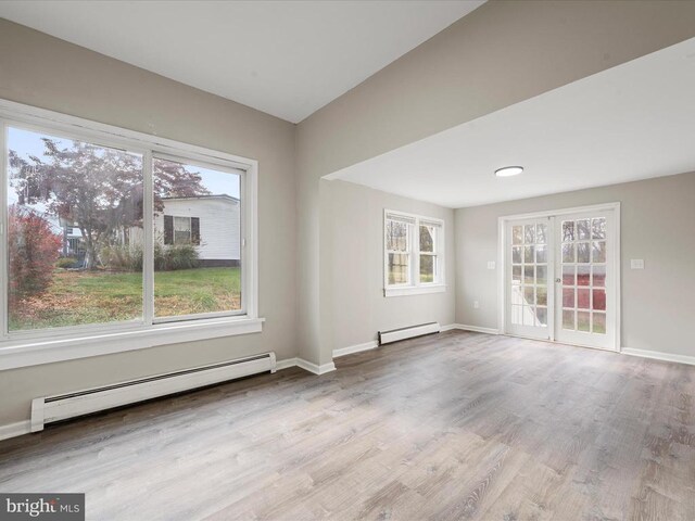 unfurnished room with a baseboard radiator and light hardwood / wood-style floors