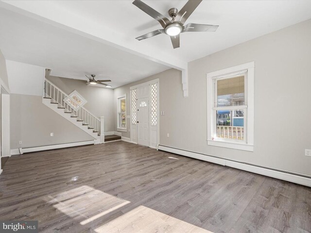 unfurnished living room with ceiling fan, wood-type flooring, and a baseboard heating unit