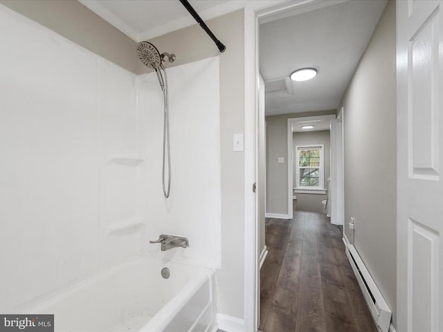 bathroom with a baseboard radiator, hardwood / wood-style floors, and washtub / shower combination