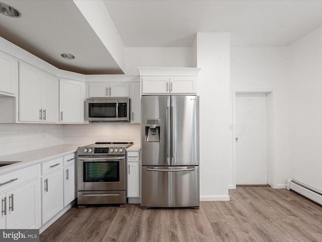 kitchen with stainless steel appliances, white cabinetry, tasteful backsplash, and light wood-type flooring