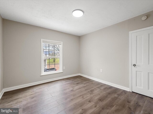 unfurnished room with hardwood / wood-style floors and a textured ceiling