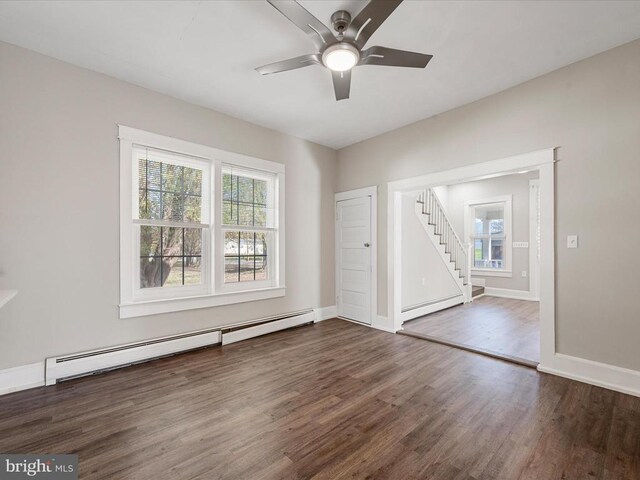 unfurnished room featuring dark hardwood / wood-style flooring, a wealth of natural light, ceiling fan, and baseboard heating