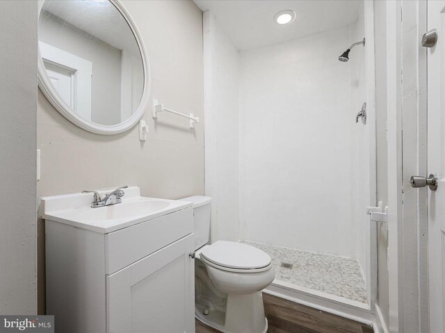 bathroom featuring vanity, wood-type flooring, walk in shower, and toilet