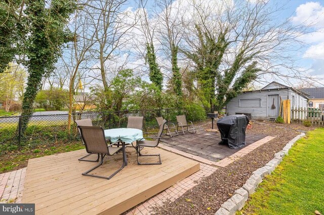 wooden deck featuring an outdoor structure and a grill