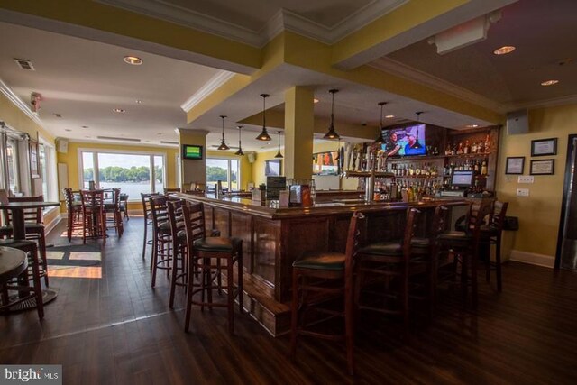 bar featuring crown molding, dark hardwood / wood-style floors, and pendant lighting