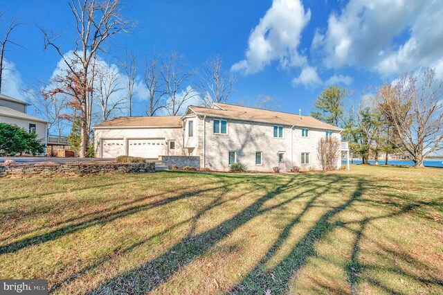 back of property featuring a water view, a garage, and a lawn