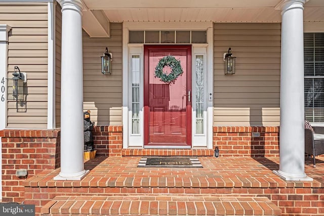 entrance to property with brick siding and a porch