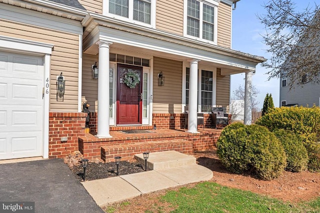 entrance to property featuring covered porch and a garage