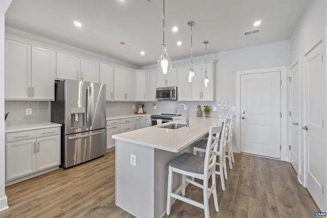 kitchen featuring pendant lighting, a breakfast bar area, light countertops, visible vents, and appliances with stainless steel finishes