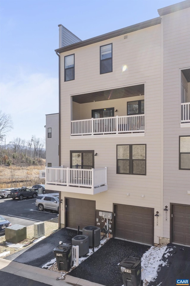 view of property with central AC, a balcony, and an attached garage