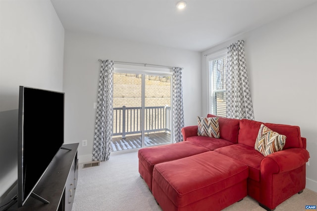 living area with light carpet, baseboards, and visible vents