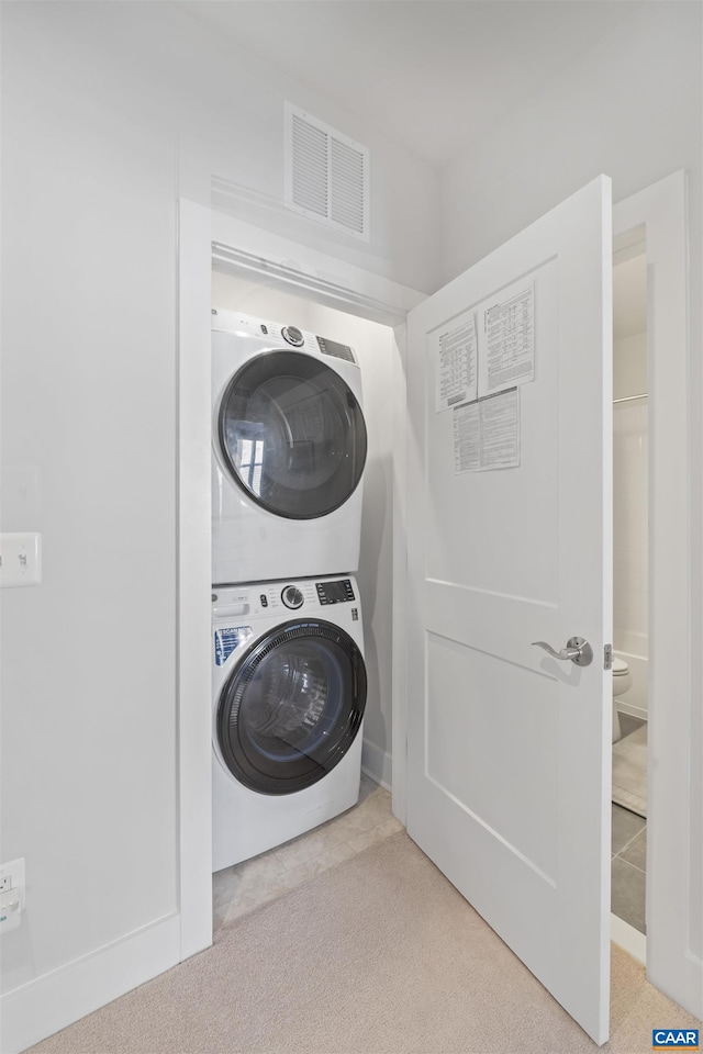 laundry room with stacked washer / dryer, laundry area, visible vents, and light carpet