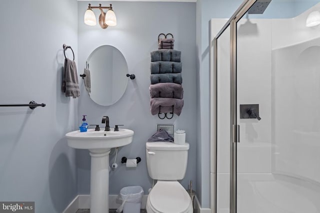 bathroom with toilet, sink, and a shower with shower door