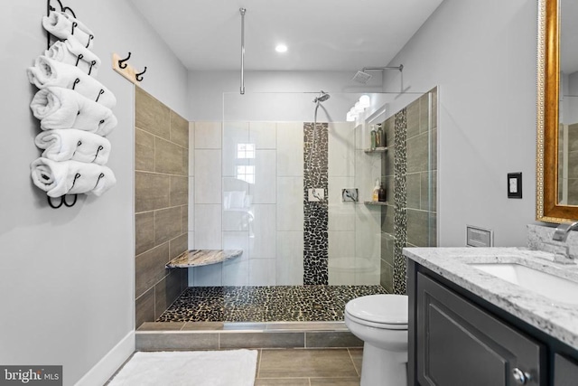 bathroom with vanity, a tile shower, tile patterned floors, and toilet