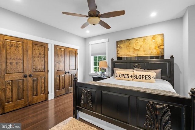 bedroom with dark hardwood / wood-style floors, two closets, and ceiling fan