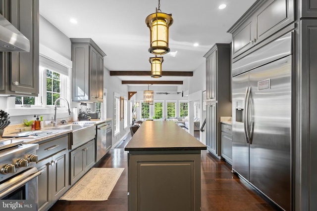 kitchen featuring a kitchen island, a wealth of natural light, high quality appliances, sink, and wall chimney range hood