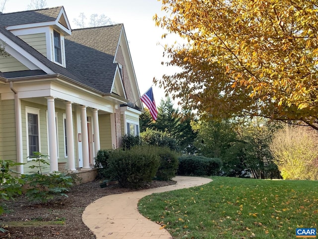 view of side of home featuring a yard and a shingled roof