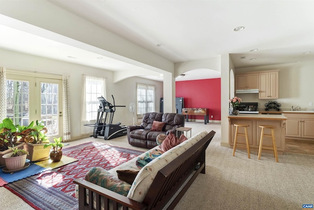 living area featuring recessed lighting, baseboards, arched walkways, and light carpet