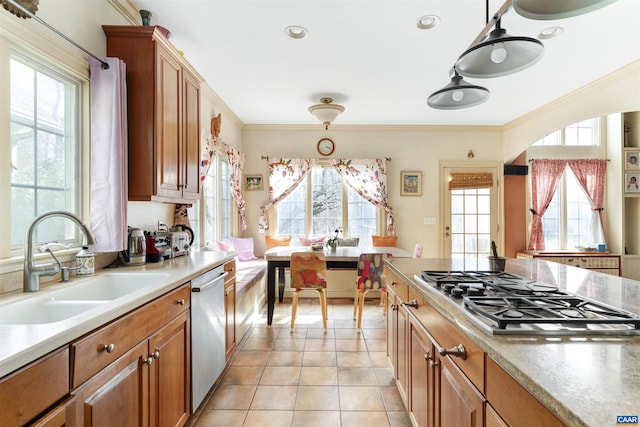 kitchen featuring light tile patterned flooring, a sink, stainless steel appliances, crown molding, and brown cabinets