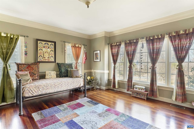 sitting room with visible vents, baseboards, wood finished floors, and ornamental molding