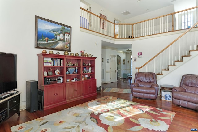 living room with visible vents, stairs, a towering ceiling, and wood finished floors