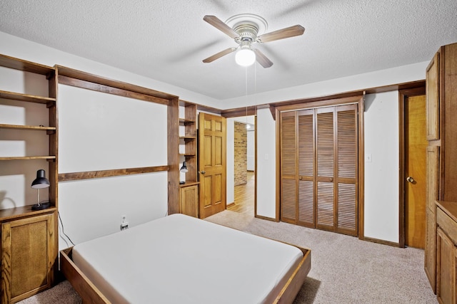 bedroom with a closet, a textured ceiling, a ceiling fan, and light carpet