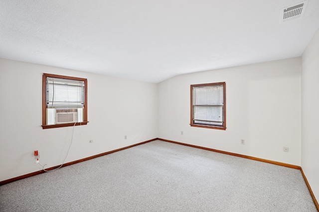 carpeted spare room featuring cooling unit, baseboards, and visible vents
