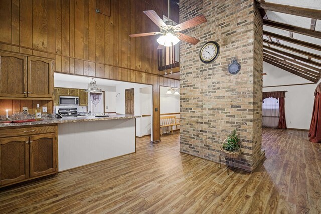 kitchen with stainless steel microwave, a ceiling fan, wood finished floors, and a towering ceiling
