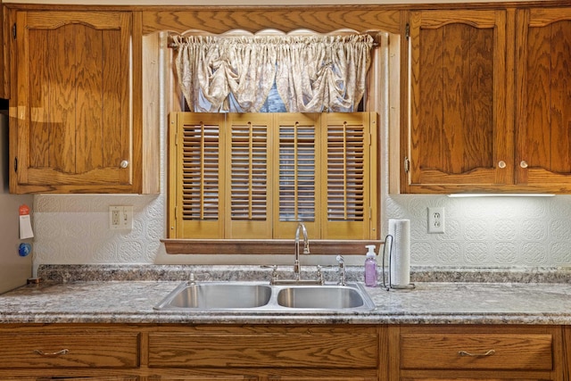 kitchen with brown cabinets, a sink, and light countertops