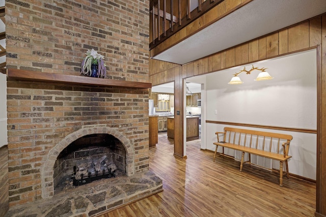 living room featuring baseboards, a towering ceiling, wood walls, and wood finished floors