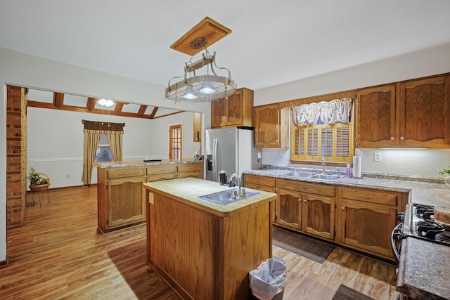 kitchen featuring wood finished floors, a sink, an island with sink, and stainless steel fridge with ice dispenser