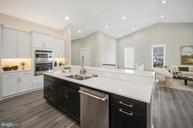 kitchen with appliances with stainless steel finishes, lofted ceiling, sink, white cabinets, and a center island with sink