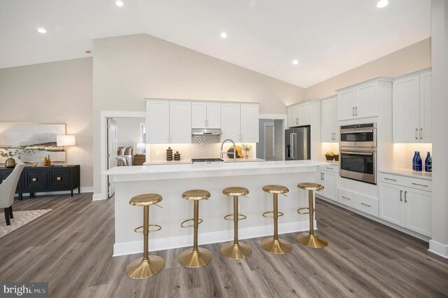 kitchen featuring a center island with sink, a breakfast bar area, white cabinets, and appliances with stainless steel finishes