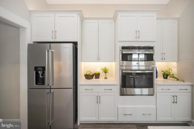 kitchen featuring backsplash, appliances with stainless steel finishes, and white cabinets