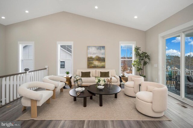 living room with a healthy amount of sunlight, vaulted ceiling, and light hardwood / wood-style flooring