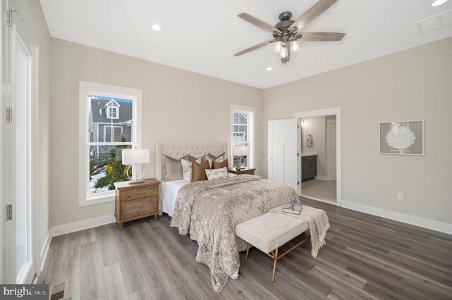 bedroom with multiple windows, hardwood / wood-style flooring, connected bathroom, and ceiling fan