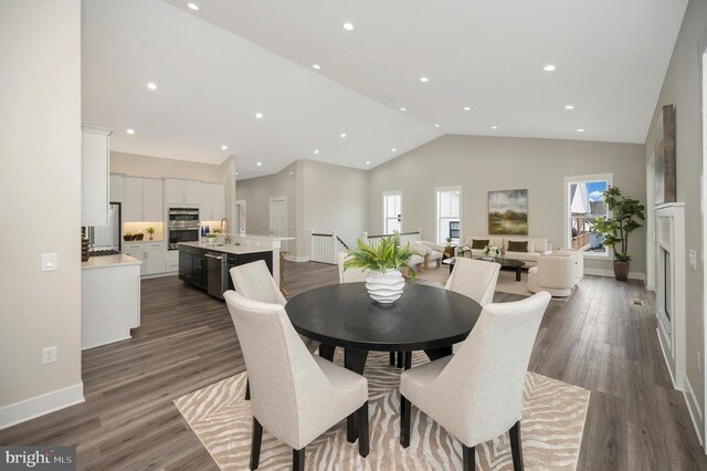 dining room with vaulted ceiling, dark hardwood / wood-style flooring, and sink