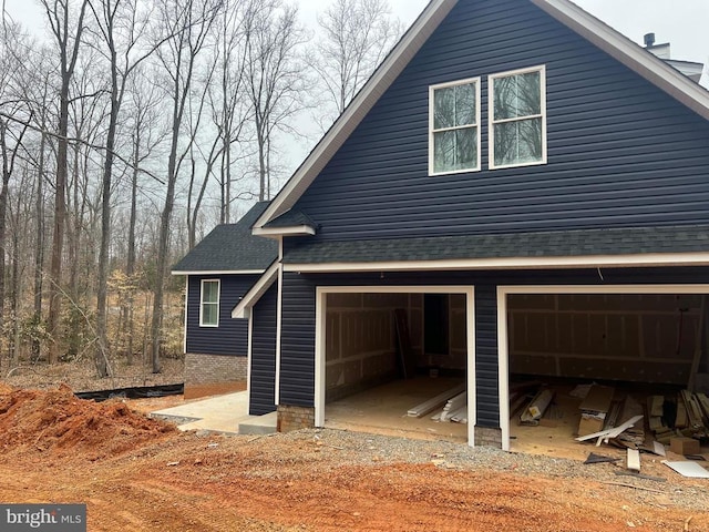 view of side of home with an attached garage and a shingled roof